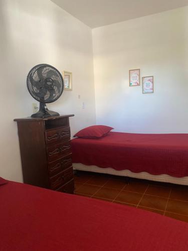 a bedroom with a bed and a fan on a dresser at Pousada da Vânia in Vespasiano