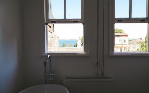 a bathroom with two windows with a view of the water at Hill House butik in Istanbul