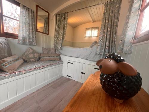 a room with a bench and a dog sitting on a table at Orchard Shepherds Hut in Calstock