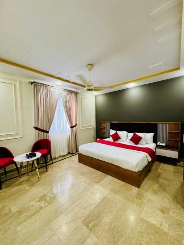 a bedroom with a bed and two chairs and a table at Holiday One Hotel & Suites - Gulshan-4 in Karachi