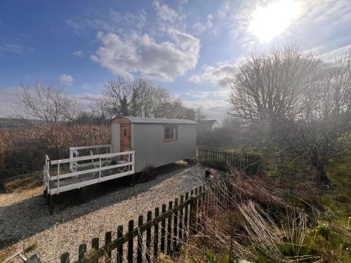 a tiny house on the side of a fence at Orchard Shepherds Hut in Calstock
