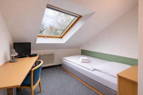 a room with a bed and a desk and a window at Silvio-Gesell-Tagungsstätte in Wuppertal