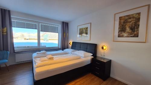 a bedroom with a bed and a large window at Panorama Apartments - Steinbock Lodges in Zell am See