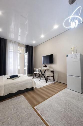 a bedroom with a bed and a white refrigerator at Современный апартамент Tandau в центре in Almaty