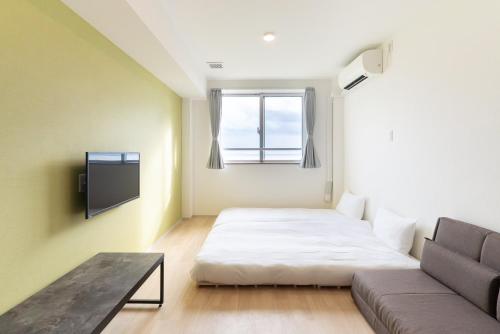 a small room with a bed and a couch at コート エトワレ マエザト-新築アパートメントホテル- in Ishigaki Island