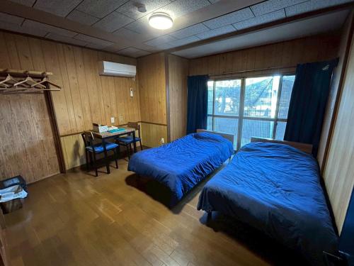 a bedroom with two beds and a desk and a table at Denim-yado Ken-健- in Tamano