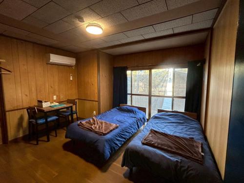 a bedroom with two beds and a desk and a table at Denim-yado Ken-健- in Tamano