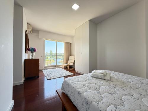 a white bedroom with a bed and a window at Secret Spot Apartment - Quinta da Barca in Esposende