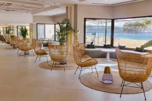 a lobby with chairs and tables and a beach at Hotel Cristina by Tigotan Las Palmas - Adults Only in Las Palmas de Gran Canaria