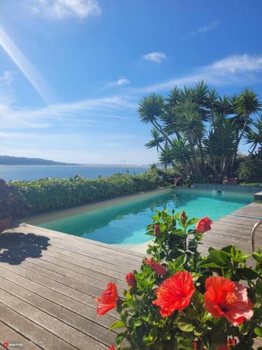 a swimming pool with red flowers on a wooden deck at Óbidos Lagoon Refuge in Foz do Arelho