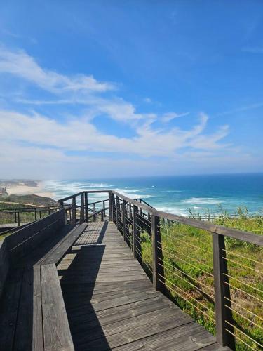 a wooden boardwalk with the ocean in the background at Óbidos Lagoon Refuge in Foz do Arelho