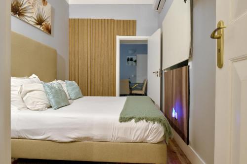 a bedroom with a bed with white sheets and pillows at Plaza House Ílhavo in Ílhavo