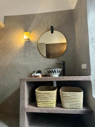 a bathroom with a vanity with a mirror and baskets at Dar Raphael in Essaouira