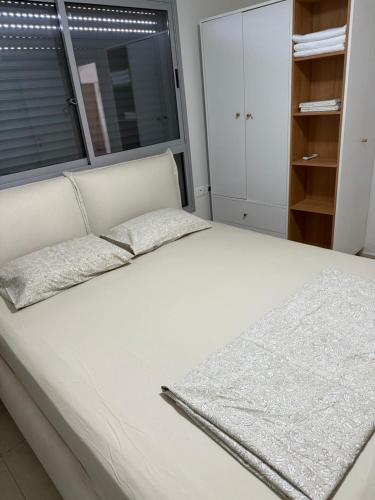 a white bed with a window in a bedroom at דירה 9 in Eilat