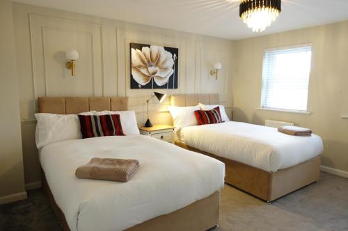a bedroom with two beds and a chandelier at 4 bedroom, Sleeps 12, Free Parking in Corby and Weldon