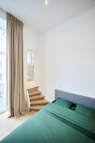 a bedroom with a green bed and a staircase at Louise City 2 in Brussels
