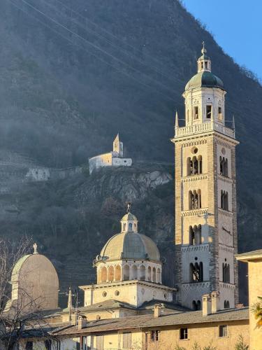 a building with a clock tower in front of a mountain at Beato Mario Apartments in Tirano