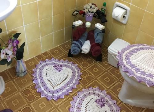 a bathroom with three crocheted mats on the floor at Passarim Chalé in Monte Verde