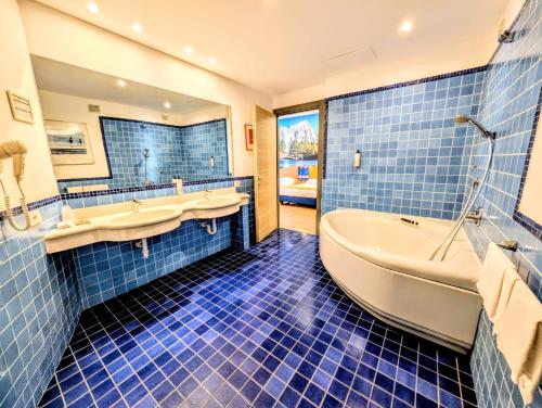 a blue tiled bathroom with a tub and a sink at Hotel Express Aosta East in Aosta