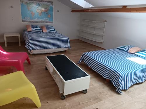 a room with two beds and a table and a chair at Vacances proche des sables d'olonne Vendée in Le Girouard