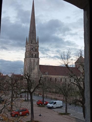 a church steeple with cars parked in front of it at Hôtel de l'abbaye in Saint-Savin
