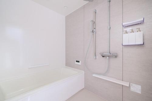 a white bathroom with a shower and a bath tub at Hakuba Caesar in Hakuba