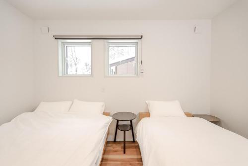 two beds in a room with a table between them at Hakuba Caesar in Hakuba