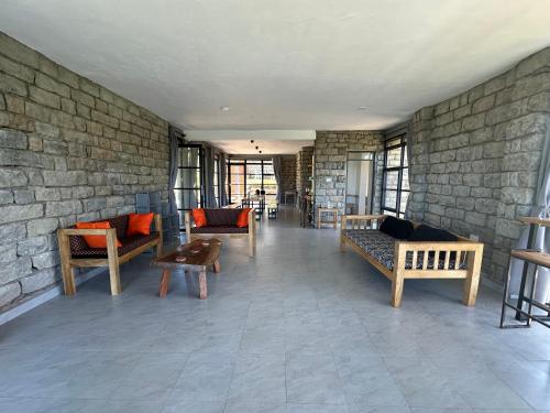 a living room with couches and a brick wall at Kapto Camp in Kapchorwa