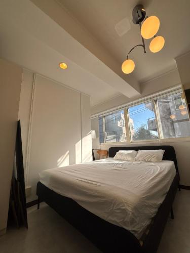 a bedroom with a bed with white sheets and two windows at Kuro House - In the middle of Hiro, Omotesando, Roppongi in Tokyo