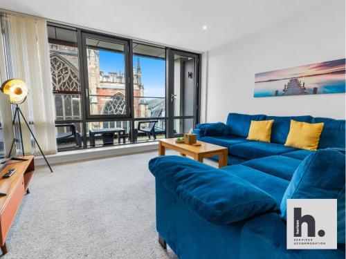 a living room with a blue couch and a large window at Contractors - Long Stay - City Centre - Free Parking - Balcony in Hull