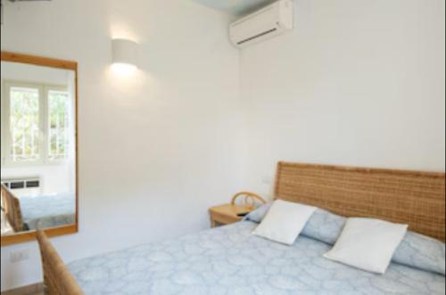 a bedroom with a bed and a mirror at Orsa sul mare a Baja Sardinia in Cala Bitta