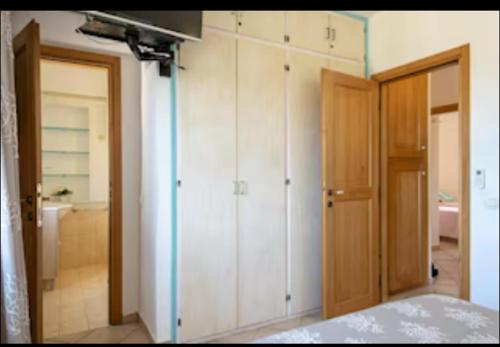 a bedroom with white cabinets and a bed and a bathroom at Orsa sul mare a Baja Sardinia in Cala Bitta