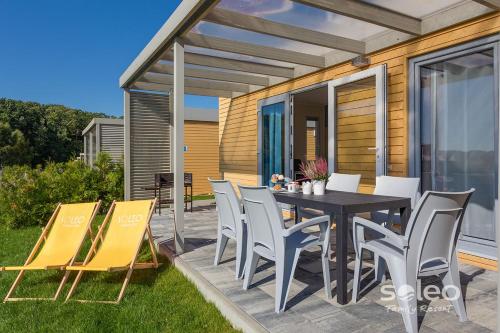 a patio with a table and chairs on the grass at SOLEO Family Resort - domki w Rewalu 3 min od Morza - 3 Baseny, 5 Jacuzzi, Sauna, ANIMACJE, Małpi Gaj, 3 Sale Zabaw, 4 Place Zabaw, 2 Restauracje in Rewal