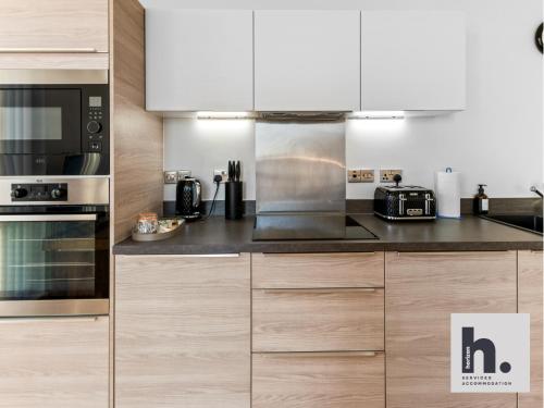 a kitchen with stainless steel appliances and wooden cabinets at Contractor Stays - 3 Units - City Centre - Siemens - NHS - Uni - Free Parking in Hull