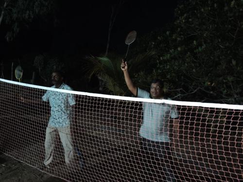 two men standing over a tennis net at night at S P Restaurant in Kallady