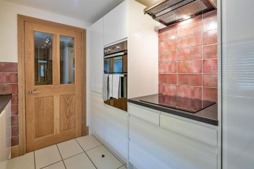 a kitchen with a wooden door and a tiled wall at Finest Retreats - Garreg Ddu in Blaenau-Ffestiniog