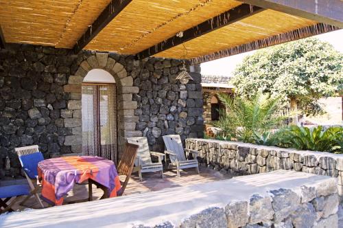 a patio with a table and chairs and a stone wall at I Dammusi di Punta Karace in Tracino