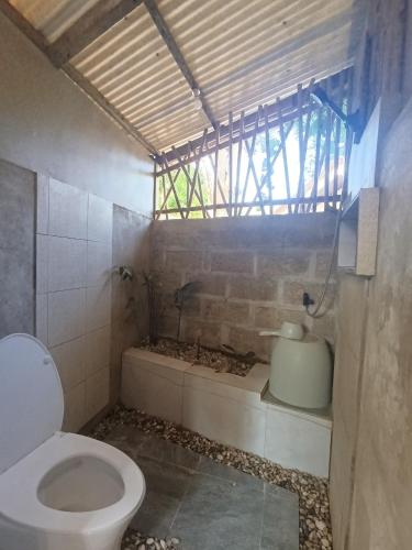 a bathroom with a toilet and a window at Kamp Tapik - Sibaltan in El Nido