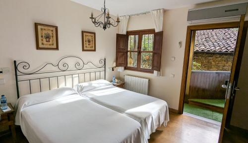 ein Schlafzimmer mit einem großen weißen Bett und einem Fenster in der Unterkunft Alojamientos Cenera in Cenera