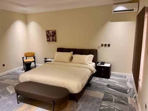 a bedroom with a large bed and a chair at Saadatus Apartment in Kaduna