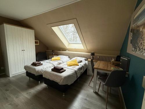 a bedroom with two beds and a table and a window at B&B Plompetorenzicht in Burgh Haamstede