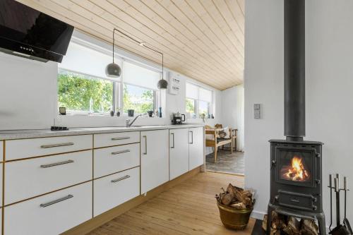 a kitchen with white cabinets and a wood stove at Sommerhus tæt på strand i Købingsmark ved Nordborg in Nordborg