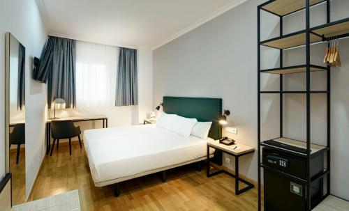 a bedroom with a white bed and a desk at Sercotel Las Casas de los Mercaderes in Seville