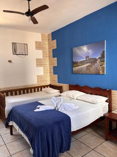 a bedroom with two beds and a blue wall at Pousada Lua Clara in Paraty