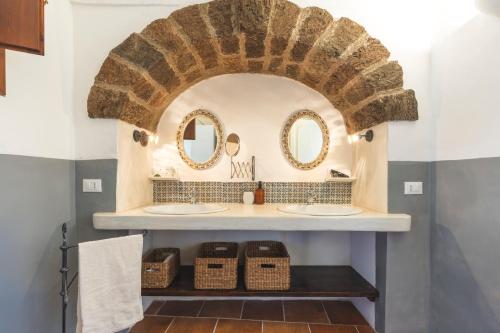 a bathroom with two sinks and two mirrors at Dammuso del Nonno in Pantelleria