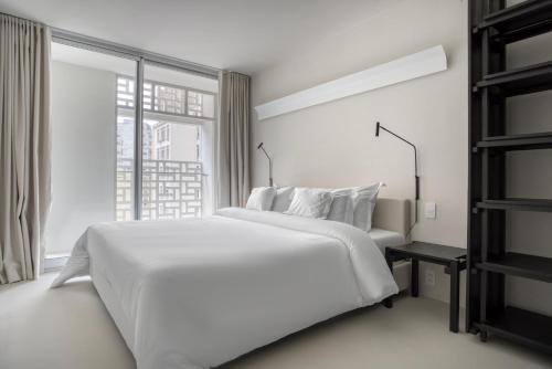 a white bedroom with a bed and a window at Tabas - Renata Edifício - Vila Buarque in São Paulo