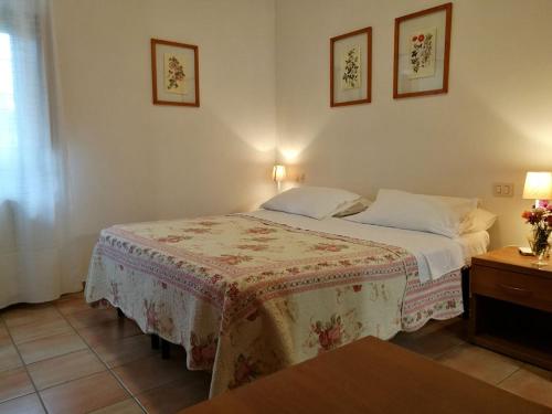 a bedroom with a bed with a table and two pictures on the wall at Rugiada Rooms in Rivotorto