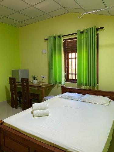 a green room with a bed and a window at DEMITHA guest in Ranna