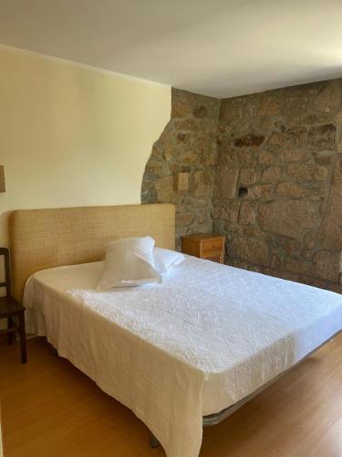 a bedroom with a bed with a stone wall at Quinta do Ferrador in Viana do Castelo