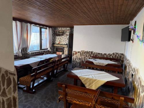 a room with wooden tables and benches and windows at къща Солунови in Dobrinishte